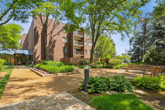 Front view of a multi-story brick building with balconies and landscaped gardens.