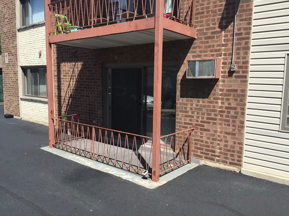 Ground level view of a multi-story brick building with exterior balcony structures.