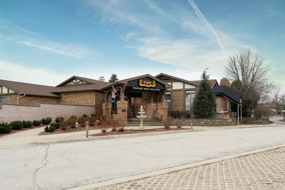Front view of a single-story brick building with a decorative fountain and entrance canopy.