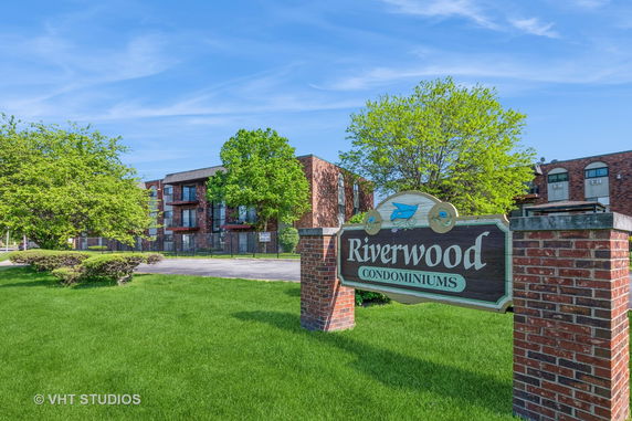 Front view of a condominium building with a sign reading 'Riverwood Condominiums'.
