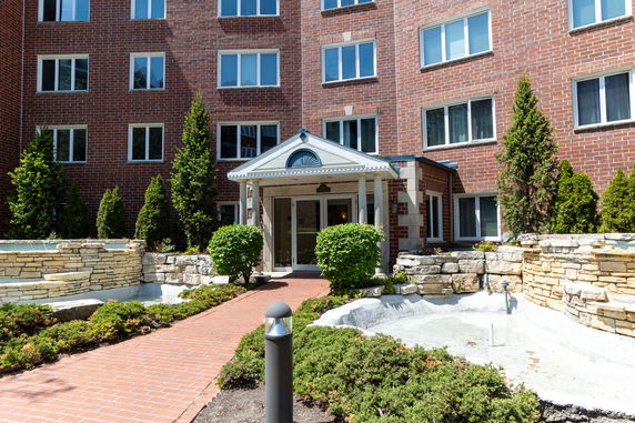 Front view of a multi-story brick building with an entrance and pathway.