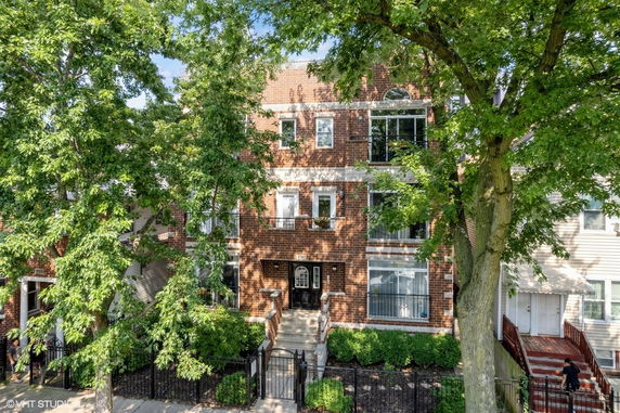 Front view of a multi-story brick house with a gated entry.