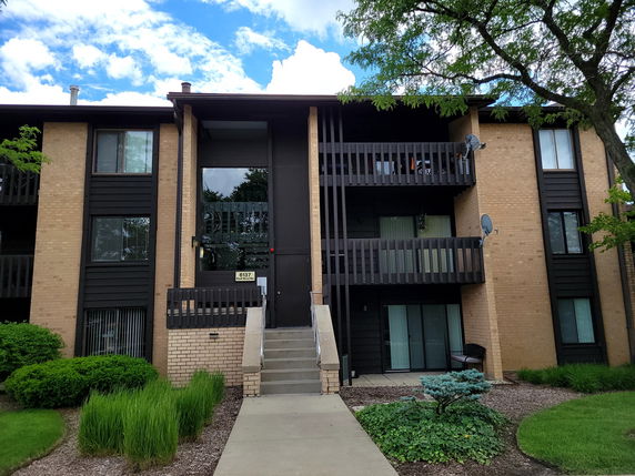 Front view of a multi-story apartment building with brick exterior and balconies.