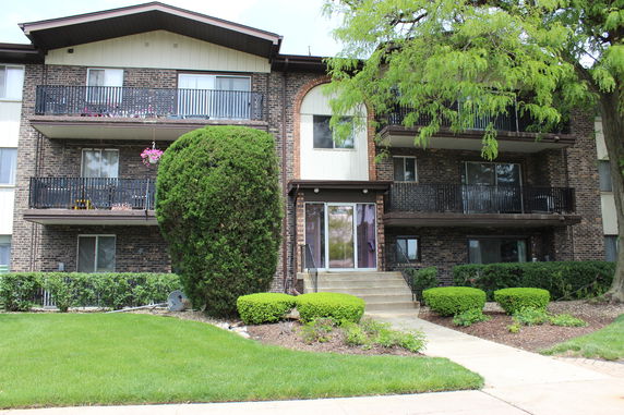 Front view of a multi-story brick apartment building with balconies.