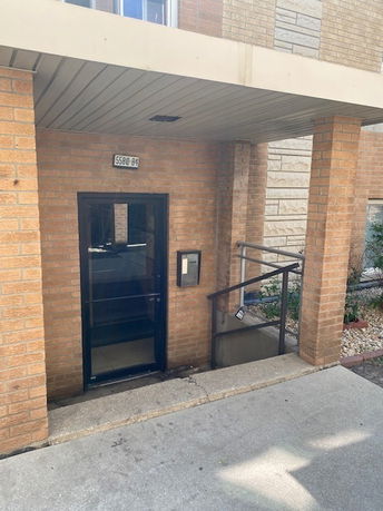 Front view of a brick building entrance with a covered entryway and steps.