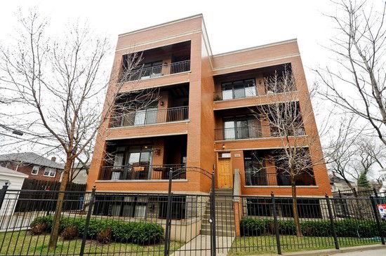 Front view of a multi-story brick apartment building with balconies.