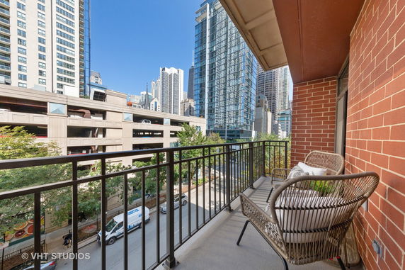 View from a balcony overlooking a street with tall buildings in an urban setting.