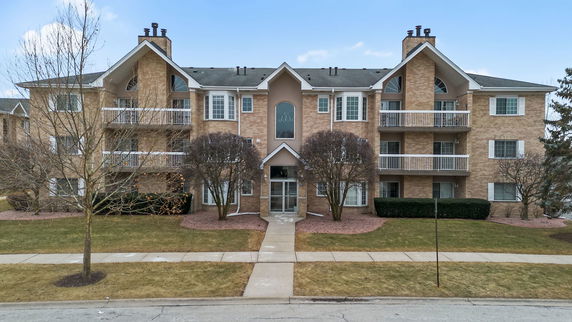Front view of a multi-story residential building with balconies and brick facade.