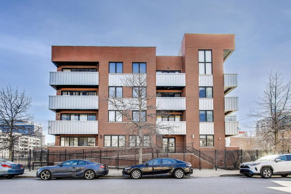 Front view of a multi-story brick building with balconies and large windows.