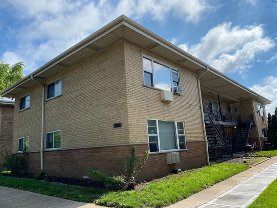 Front view of a two-story brick apartment building with external staircases.