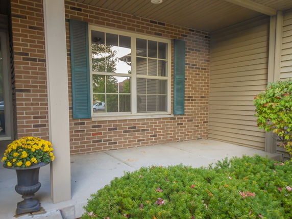 Front view of a house with a brick facade and window with blue shutters.