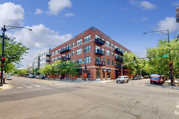Front view of a multi-story brick apartment building on a corner street.
