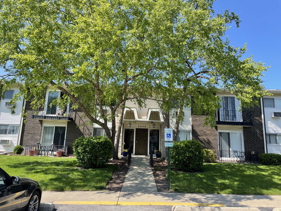 Front view of a multi-story residential building with balconies and a central entrance.