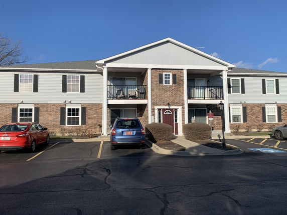 Front view of a two-story building with brick and siding exterior and parking area.