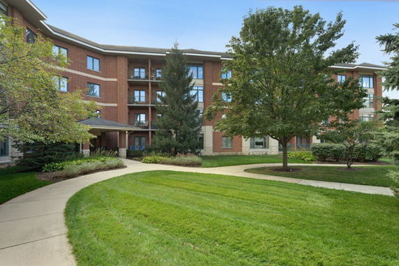 Front view of a multi-story building with red bricks and multiple windows, surrounded by greenery.