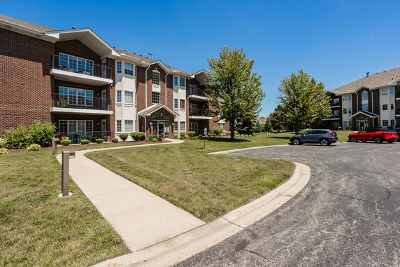 Front view of a multi-story apartment building with red brick exterior and balconies.