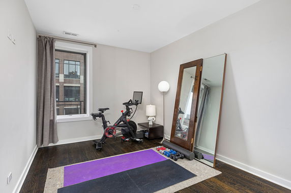 Room with exercise equipment including a stationary bike and yoga mats.