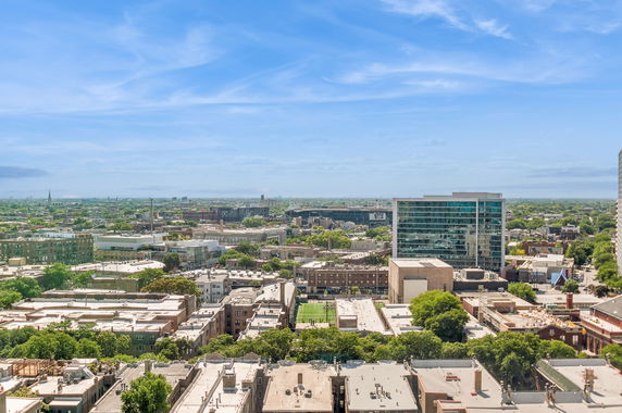 Panoramic view of a cityscape with buildings and greenery under a clear blue sky.