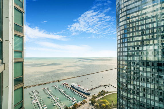 Panoramic view of a large body of water with a marina and boats, seen from between two high-rise buildings.