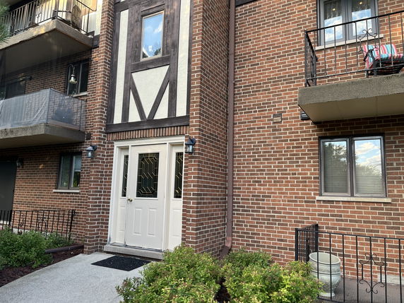 Front view of a brick apartment building with balconies.