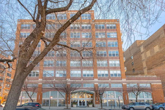 Front view of a multi-story brick building with large windows.