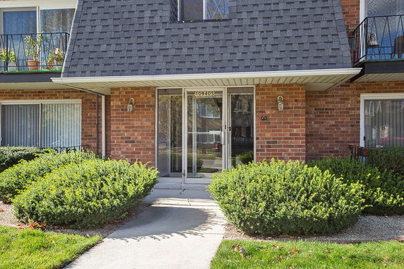 Front view of a brick building with a covered entrance and large windows.