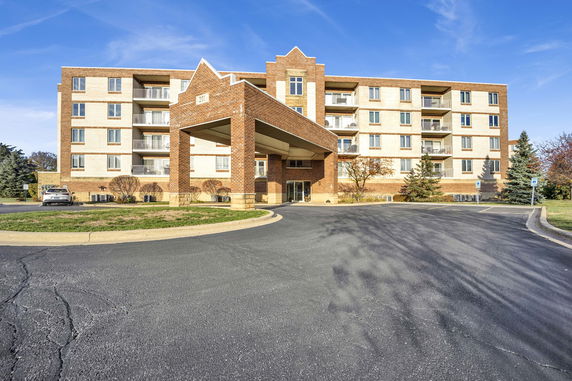 Front view of a multi-story brick apartment building with balconies.