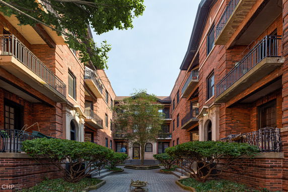 Front view of a multi-story brick apartment building with balconies.