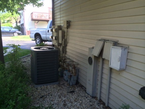 Side view of a building with air conditioning unit and utility meters installed.