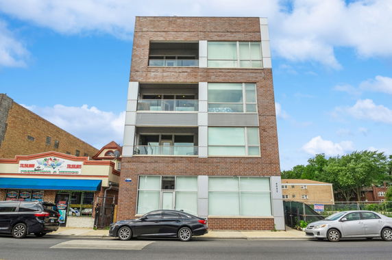 Front view of a multi-story brick building with large windows.