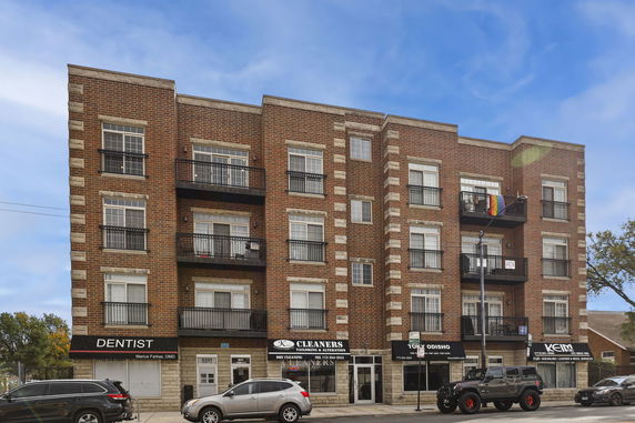 Front view of a multi-story brick building with commercial spaces on the ground floor.