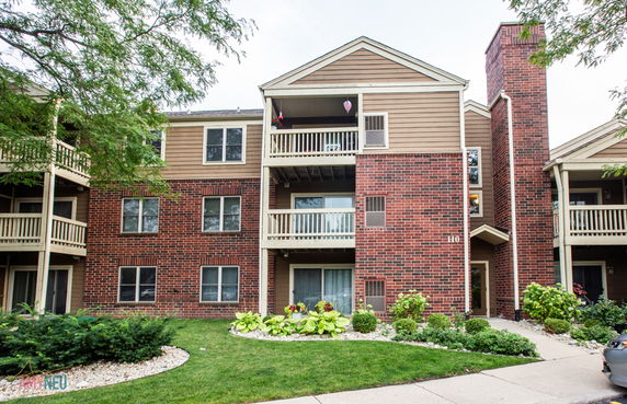 Front view of a multi-story residential building with brick exterior and balconies.