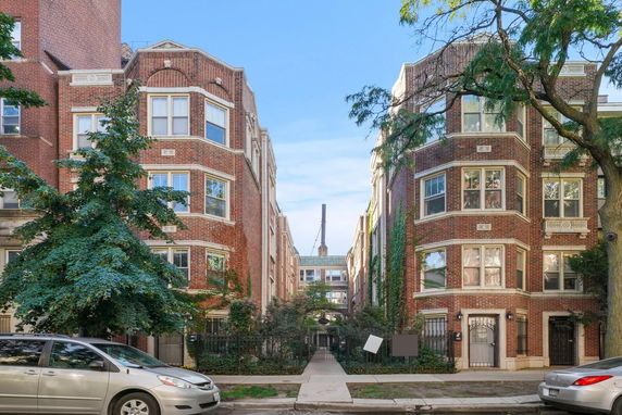 Front view of a symmetrical brick apartment building with multiple windows and gated entrances.