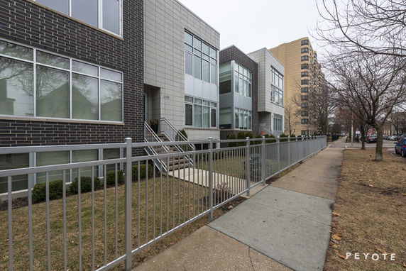 Front view of modern multi-story building with large windows and brick facade.