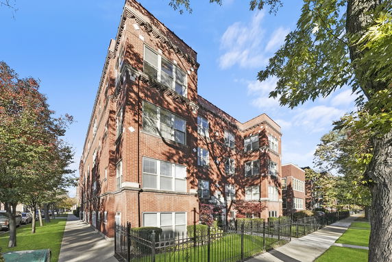 Front view of a multi-story brick building with large windows.