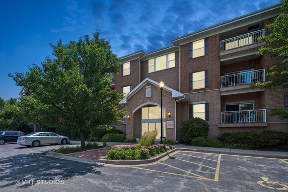 Front view of a multi-story brick building with balconies and a well-lit entrance.