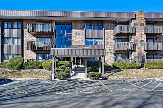 Front view of a multi-story apartment building with balconies and a covered entrance.