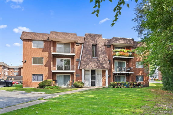 Front view of a multi-story brick apartment building with balconies.