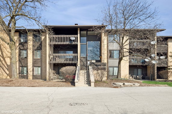 Front view of a multi-story apartment building with balconies and central entrance.