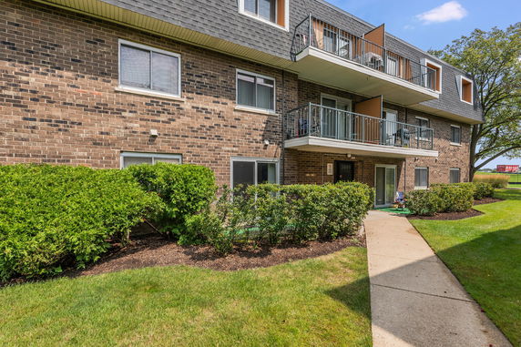 Front view of a multi-story brick apartment building with balconies.