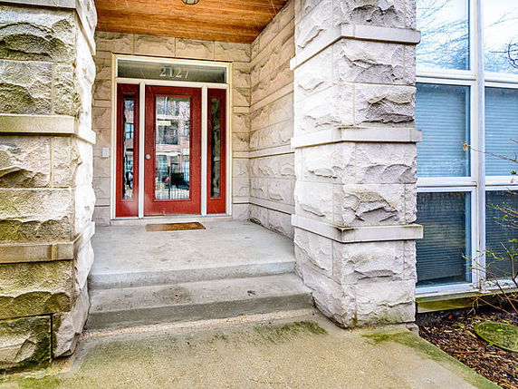 Front view of a building entrance with stone walls and a red door.