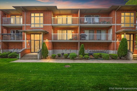 Front view of a multi-story brick building with balconies and landscaping.