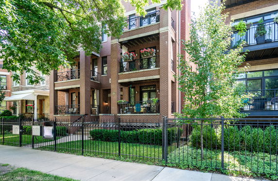 Front view of a multi-story brick apartment building with balconies.