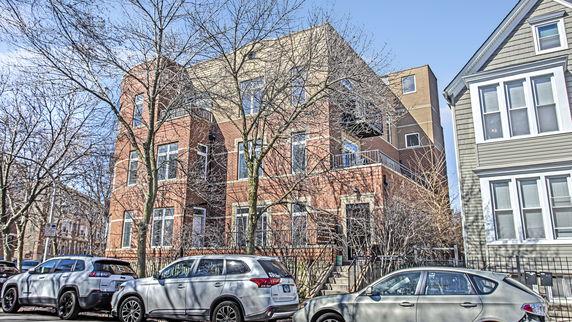 Front view of a multi-story brick building with balconies and large windows.