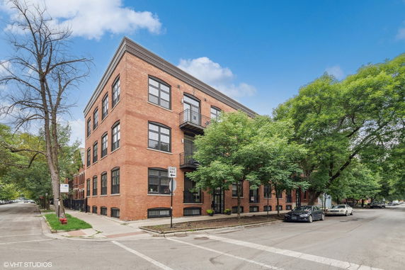 Front view of a multi-story brick apartment building on a street corner.