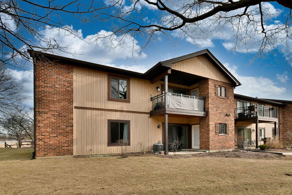 Front view of a two-story building with a combination of brick and wood siding, featuring balconies.