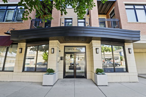 Front view of a building entrance with large windows and plants.
