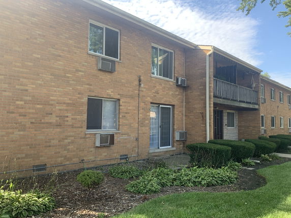 Front view of a brick two-story apartment building with multiple air conditioning units.
