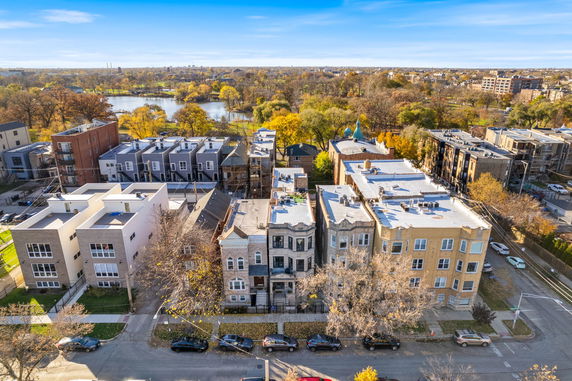 Aerial view of a residential neighborhood with multi-story houses and a nearby lake, surrounded by trees.