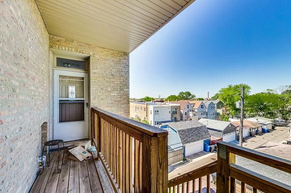 View from a balcony overlooking rooftops and a neighborhood street.